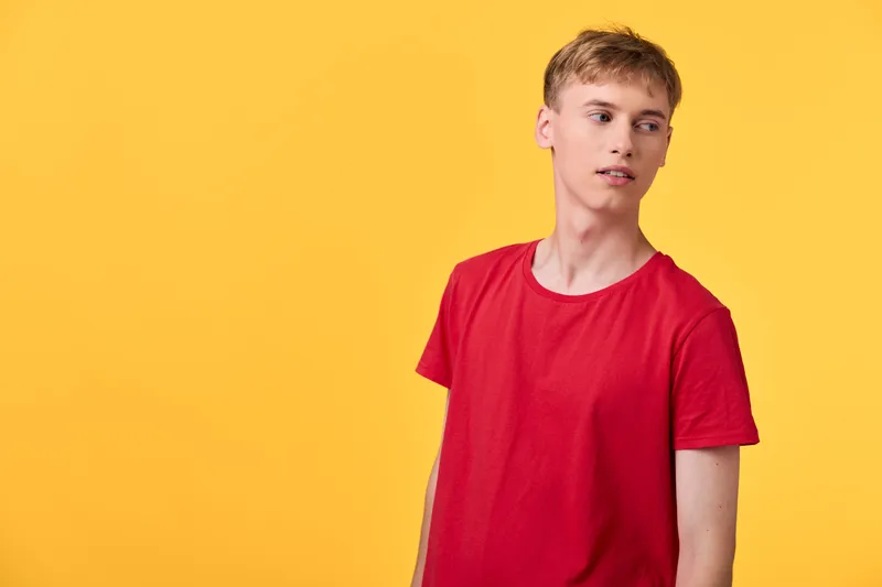 Red shirt and casual pose against a bright yellow background, clean studio setting with soft lighting, capturing fashion, warmth, and a relaxed, confident mood in a minimal lifestyle frame