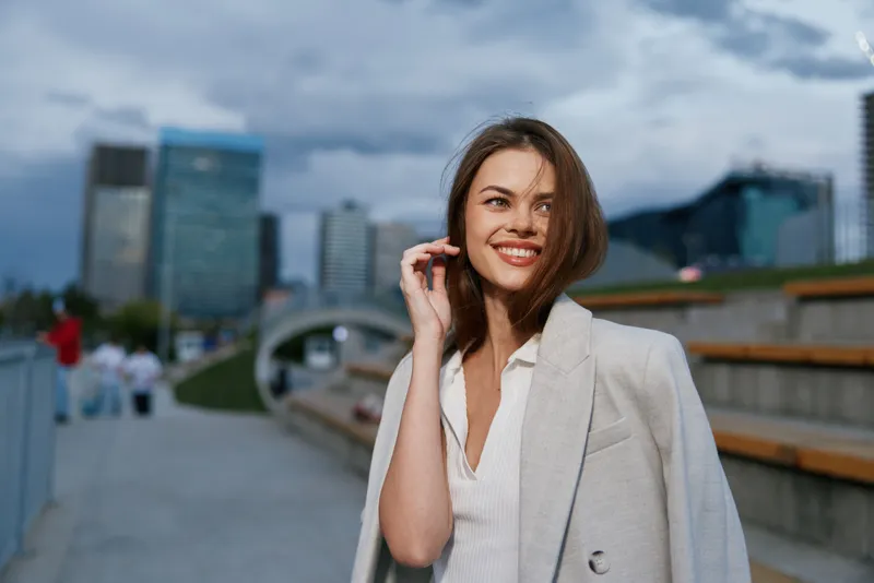 confident woman in light beige coat smiling outdoors urban business environment smiling woman autumn fashion