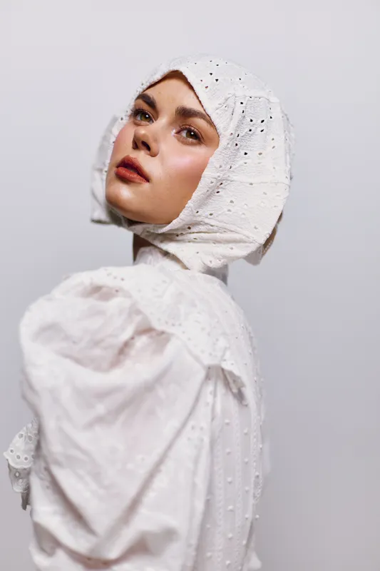 Female model in white vintage dress and headscarf, showcasing elegance and style against a neutral background Perfect for fashion and seasonal themes