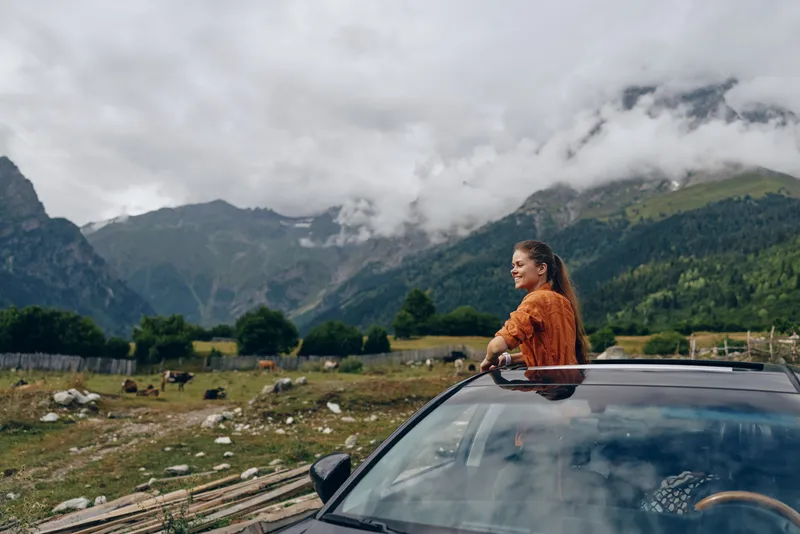 Woman in car sunroof, mountains roadtrip, authenticity inclusivity