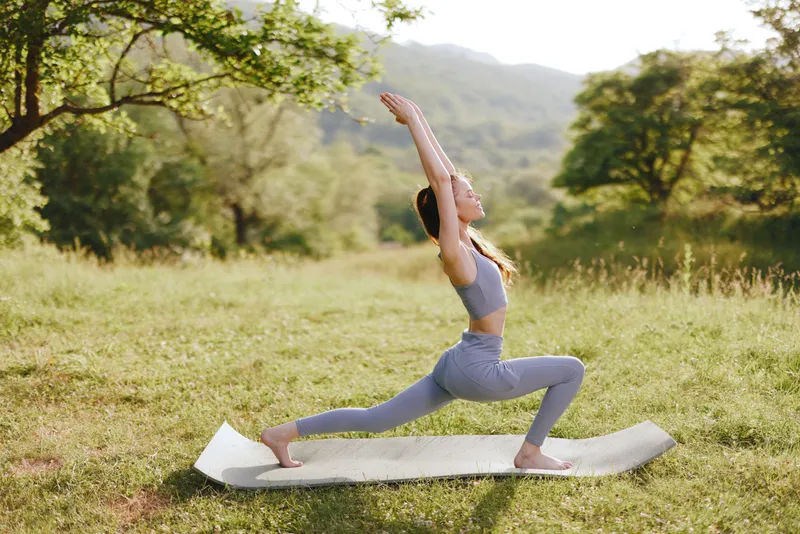 Young woman practicing yoga in a serene outdoor setting, wearing athletic apparel, showcasing strength and tranquility in nature