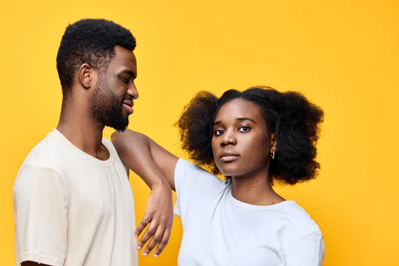 A vibrant portrait of a young African couple showcasing joy and connection, adorned in casual outfits against a bright yellow background, embodying love and togetherness