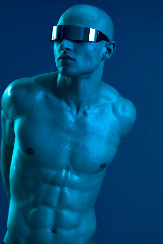 Powerful man with futuristic sunglasses, showcasing a striking blue light background, creating a strong and captivating atmosphere in this unique image.