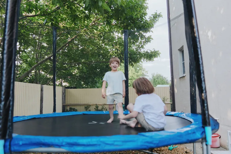Happy children playing on a trampoline, enjoying their childhood. The bright atmosphere is filled with laughter and joy as they bond outdoors in the sun. ###