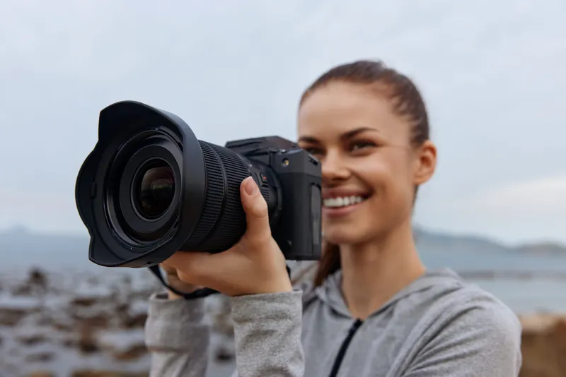 Young woman capturing nature photography with a camera, showcasing her passion for photography in a serene outdoor setting