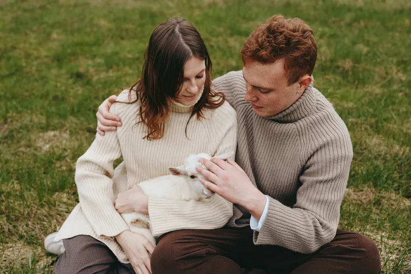 Couple lifestyle family animals goat kid affection outdoor moment nature, cuddle gentle cozy serene bond warmth countryside calm portrait weather sweater comfort harmony present companionship love