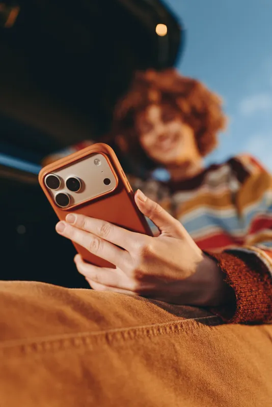 Woman lifestyle, close up holding smartphone for selfie on cozy couch indoors, warm light, relaxed home atmosphere, communication with friends, casual living room background, soft focus, today