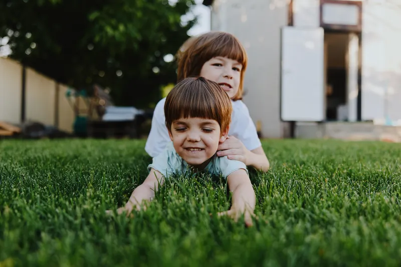 Happy children playing together on the grass in a sunny backyard, enjoying a carefree moment of joy and laughter in the fresh air.