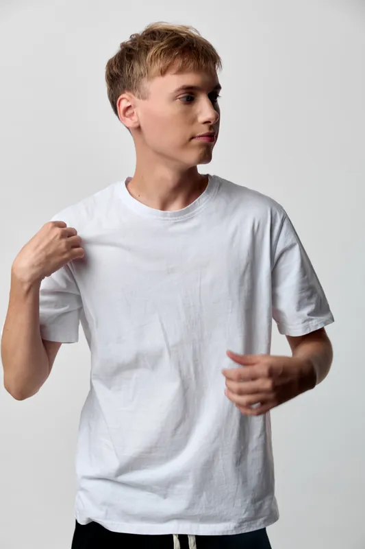 Teenage boy in a plain white tshirt strikes a casual pose against a neutral studio backdrop, showcasing relaxed style and simple everyday fashion for versatile lifestyle imagery