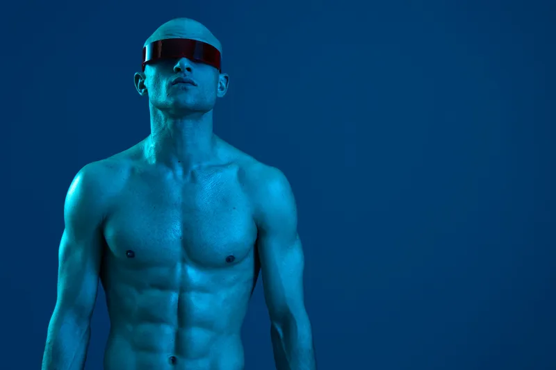 Stylish man in futuristic sunglasses against a blue background, showcasing confidence and modern fashion in a captivating and artistic portrait design.