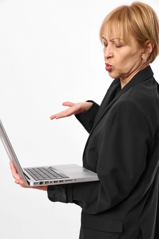 Woman holding laptop and typing, shows frustration with open hand gesture, office work concept, serious expression, isolated on white background, technology.