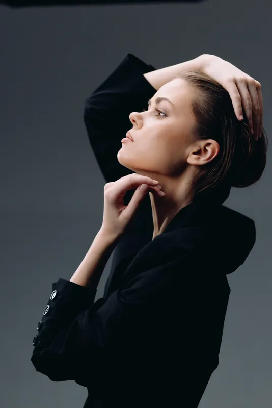 Elegant woman posing in black outfit with thoughtful expression, fashion style, studio background, soft lighting, beauty concept