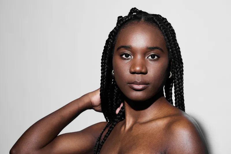 Portrait of an African woman with braided hair, showcasing natural beauty and confidence against a plain light background