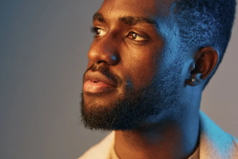 A close up portrait of a confident young Black man with a beard, showcasing strong emotions, ideal for promoting self esteem and personal growth themes