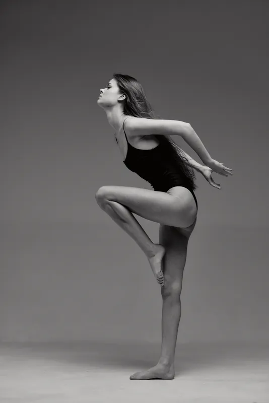 Black and white graceful woman dancer in a dynamic pose expressing balance and strength in studio.