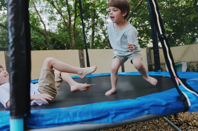 Joyful boys playing on a trampoline, enjoying a sunny day outdoors with laughter and excitement. Perfect for capturing childhood moments and playfulness.