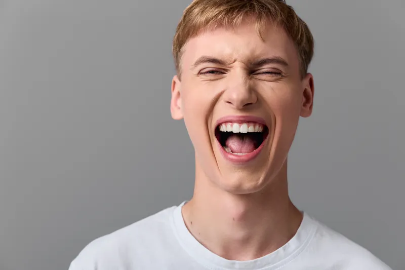 Laughter, man, wide smile, and joyful expression captured in a candid moment, showcasing happiness and an open mouth during a lighthearted reaction for marketing use in media.
