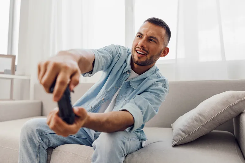 Engaged man enjoying a gaming experience, reflecting a blend of work-life blur and men's mental health while embracing authentic imperfection in a cozy atmosphere.