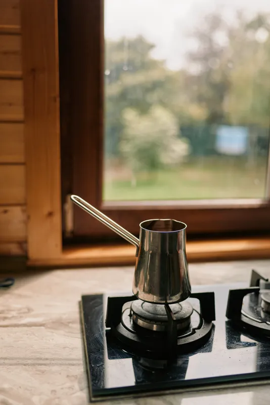 kettle stove burner kitchen metal warm light through window rustic wooden kitchen scene showing domestic cooking moment in a calm morning