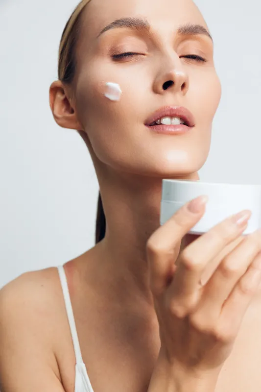 Woman, skincare, beauty, cream, face, eyes closed, clean background, wellness, gentle moisturizing, soft natural light, close up portrait, calm self care ritual, smooth skin