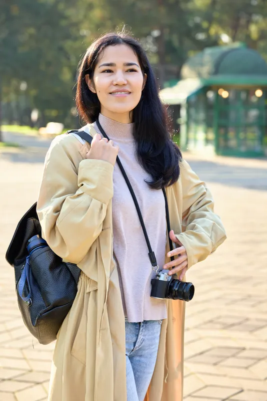 Photography, woman, outdoors, camera, backpack, park, casual, fashion, lifestyle, daylight captures a serene park stroll with a traveler photographing moments under warm sun