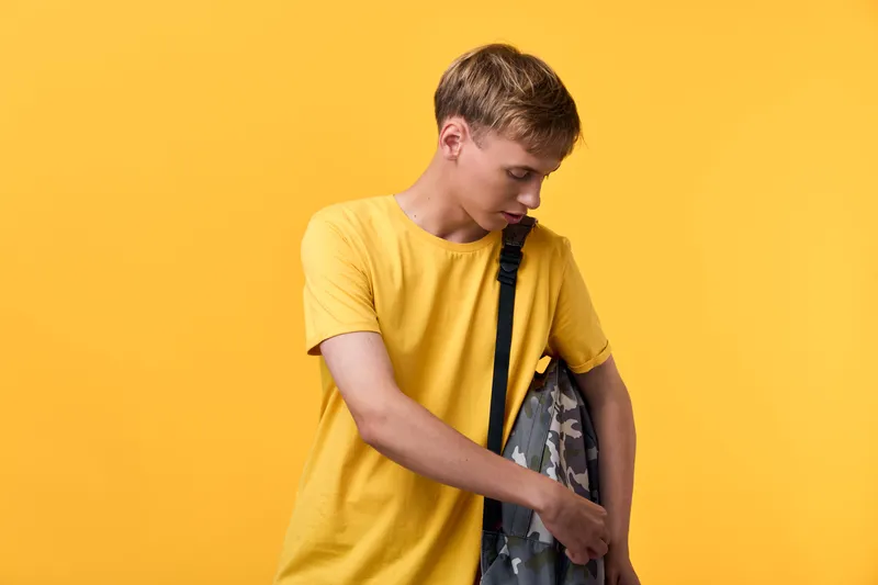 Yellow, boy, casual, fashion, model, shirt, jacket, background, backpack, studio, Teen boy in a yellow tshirt holds a jacket over his shoulder against a bright yellow background with a casual fashion