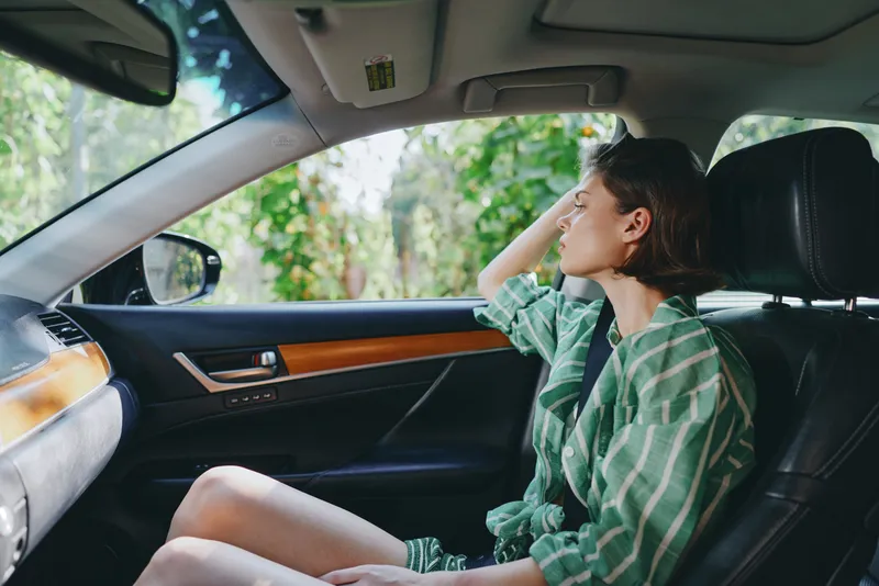 Woman seated in a car interior, gazing out the window, capturing a calm, candid moment inside a modern vehicle.