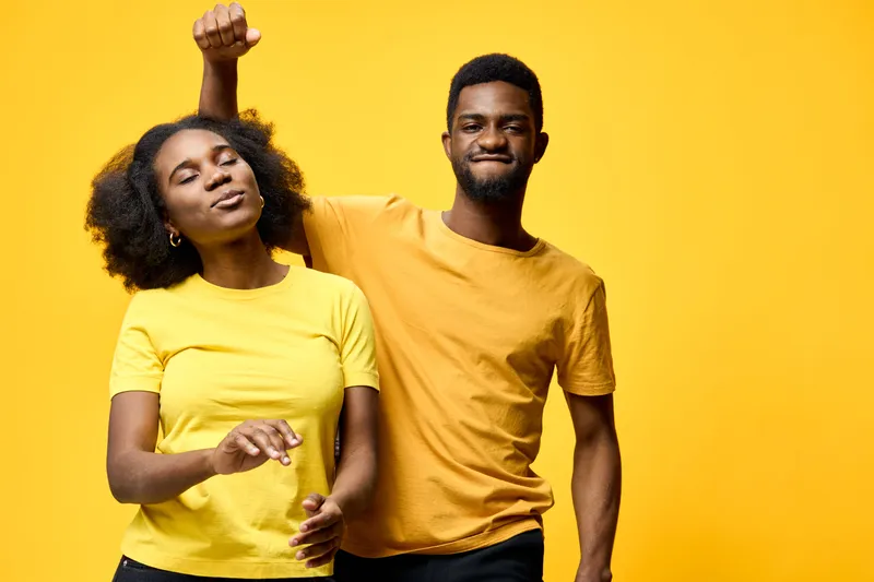 Happy diverse couple dancing joyfully with vibrant yellow background, portraying love and connection through vibrant colors and festive energy