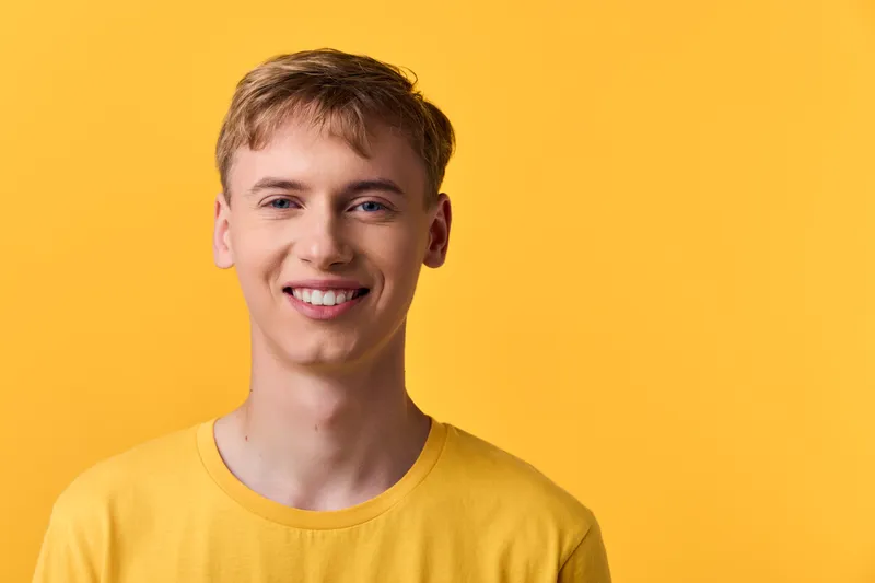 Smiling man in a yellow t shirt against a bright yellow backdrop, conveying optimism, friendliness, and casual lifestyle vibe for marketing or advertising use.