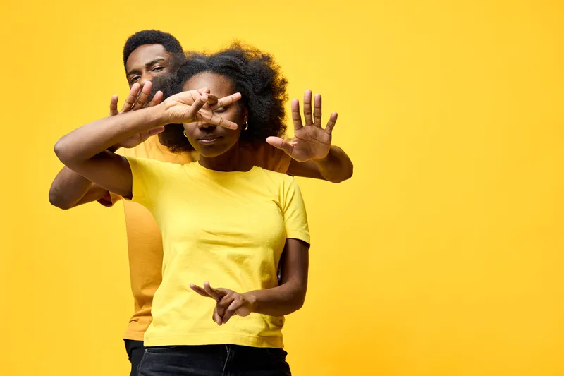 Happy couple playful pose against a vibrant yellow background, wearing casual outfits perfect for romance and joy themes in photography