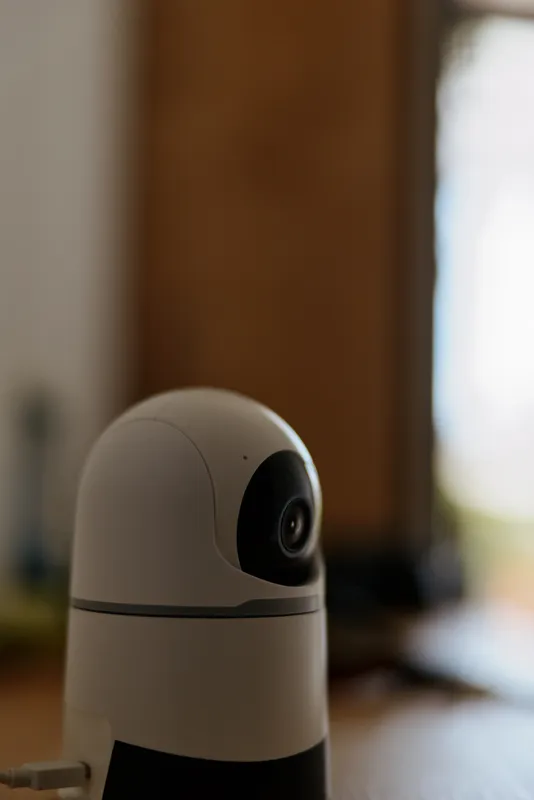 Close up of a compact home camera on a kitchen counter, warm indoor lighting, emphasizing security, privacy, and smart living concepts for modern daily life.