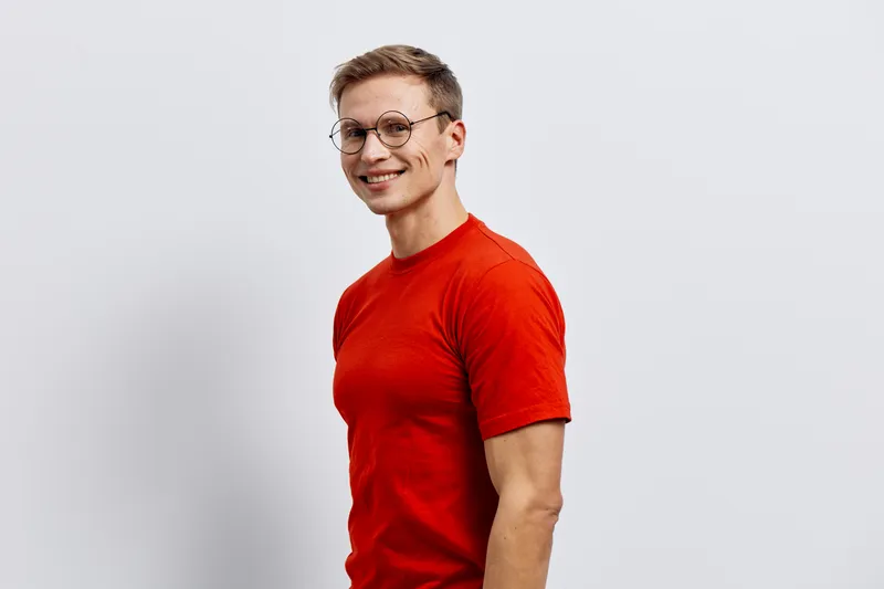 smiling man wearing glasses red t-shirt posing standing side view looking camera digital nomad concept