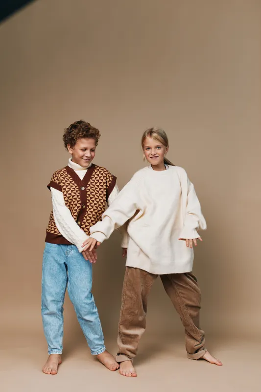 Authentic scene shows two children in cozy casual outfits enjoying play, capturing genuine emotion and everyday moments that reflect school life and youthful imagination.