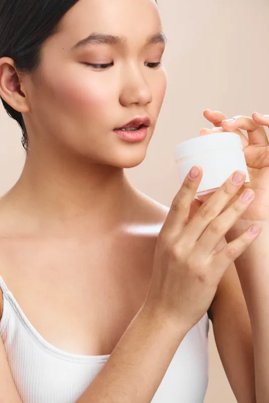 asian woman gently applies cream in a calm skincare scene, close up on smooth skin and soft lighting, conveying mindfulness, selfcare, and graceful beauty in a quiet routine.