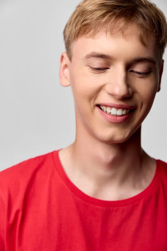 Smiling man wearing a red shirt closeup of happiness and warmth with a relaxed casual style soft lighting and cheerful mood in a simple studio setting