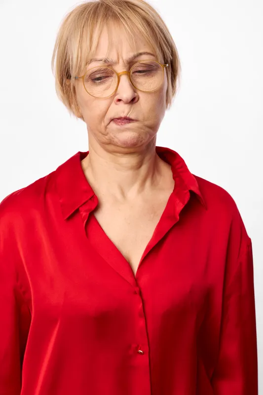Elderly woman portrait with glasses, wearing a red blouse, eyes closed and calm expression, indoor studio light, plain white background, copyspace, simple