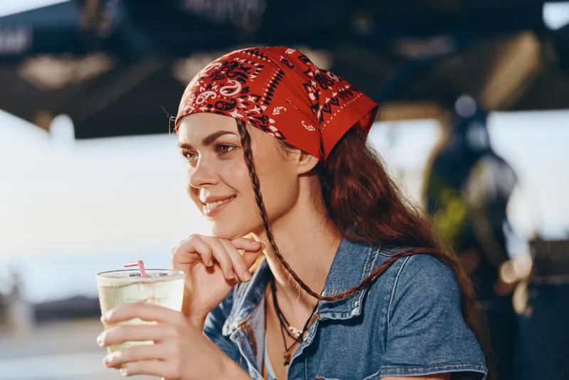 lifestyle woman enjoying summer drink in modern boho-western denim street style with film color tone, relaxed mood, casual outfit, natural light, vibrant colors