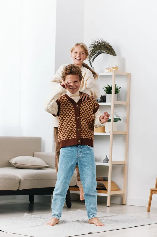 Authentic moment of children at home, a playful scene of siblings in casual school attire enjoying a lighthearted game, natural expression and spontaneous joy.