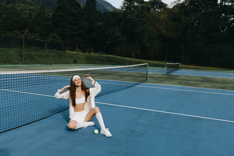 Young female tennis player in sporty attire, smiling on the court, showcasing an active lifestyle Bright, vibrant colors capture the energy of the sport
