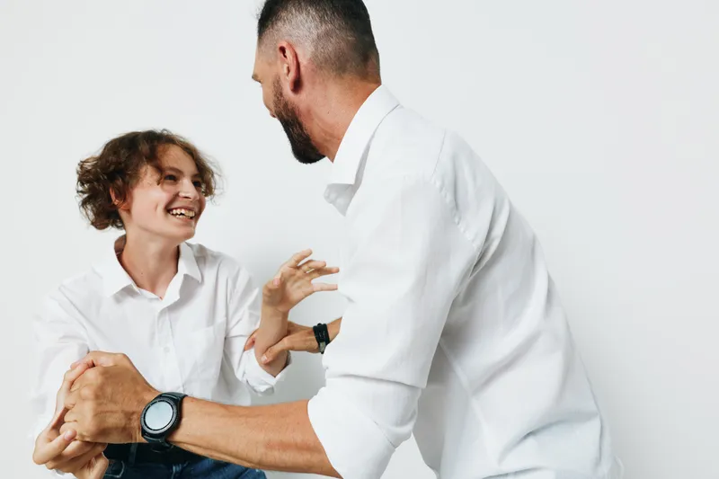 A professional man engages with a smiling colleague in a bright studio, expressing confident emotion and collaborative energy against an isolated colorful background.