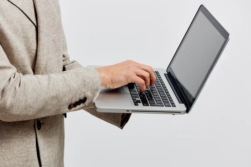 Businesswoman holding a laptop computer in her hands, wearing a beige blazer, on plain white background, modern technology, professional workspace, corporate setting, freelance work, digital business.