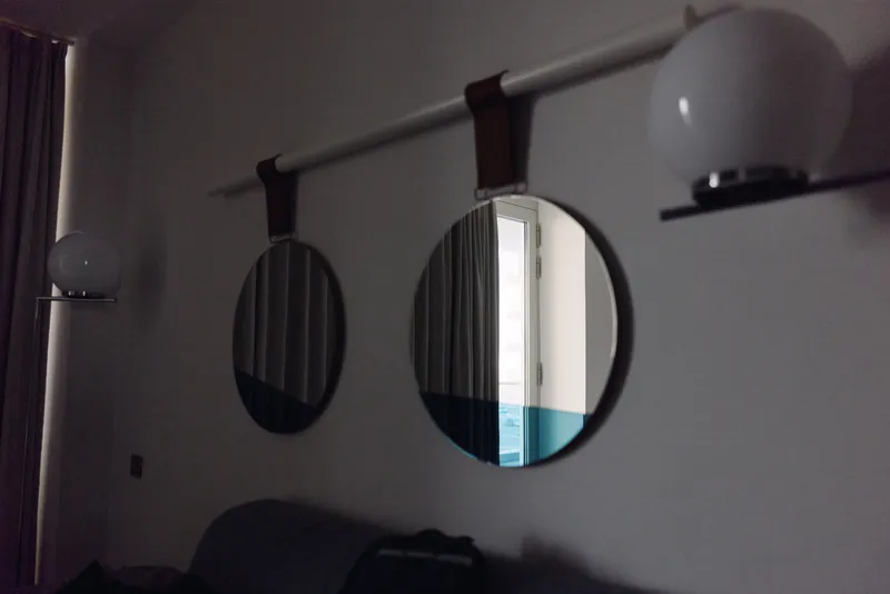 Living room with round wall mirrors, pendant lamps and soft lighting, a cozy sofa and drapes. Modern interior decor with reflective surfaces creating a calm, stylish home atmosphere.