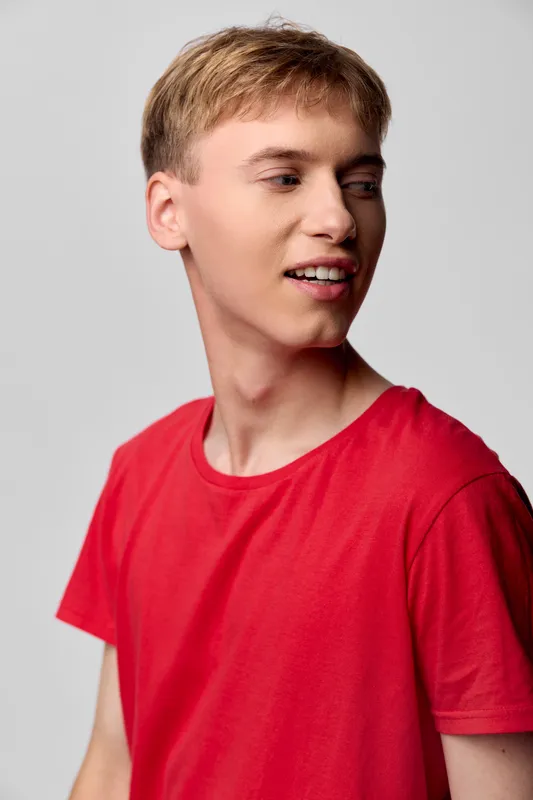 Young man, red t shirt, casual fashion, side profile, studio shot, male model, contemporary style, youth lifestyle, fashion photography, relaxed pose, suitable for lifestyle or apparel stock