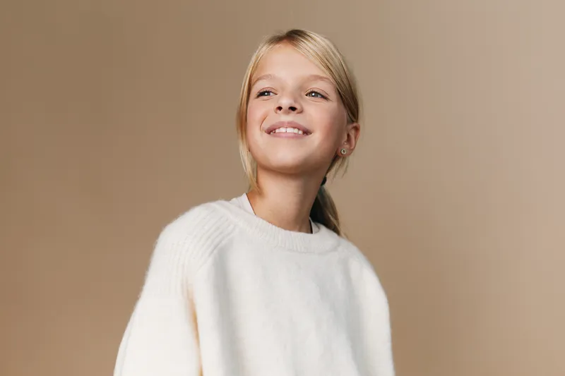 Authentic lifestyle image featuring a cheerful student in a soft white sweater, capturing genuine confidence, playfulness, and everyday school moments.