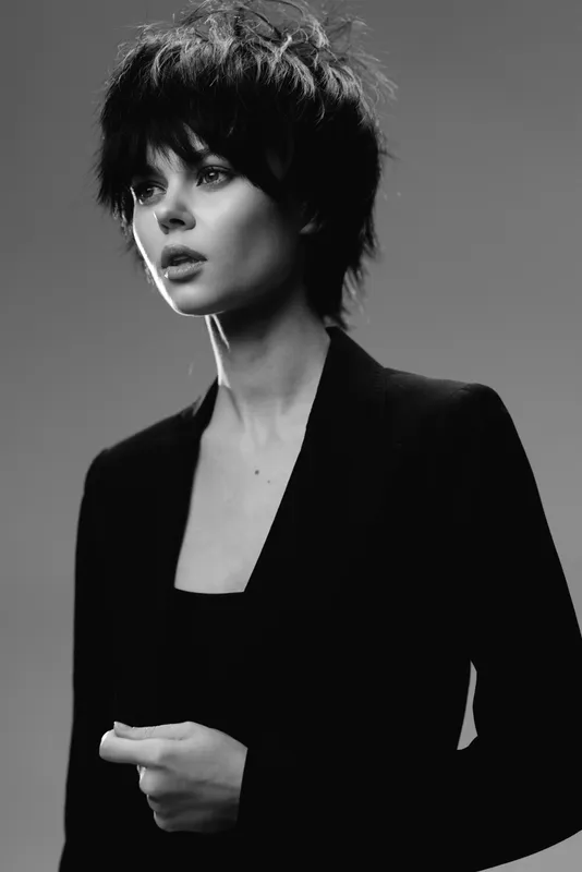 Black and white portrait of a thoughtful woman with short hair wearing a black blazer in studio lighting.