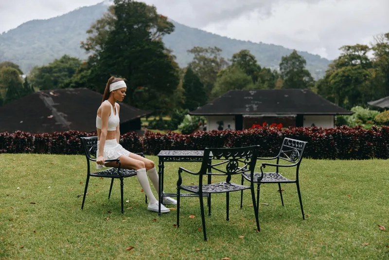 A focused young woman in sportswear sits in an outdoor setting, emphasizing health, fitness, and relaxation amidst a natural backdrop