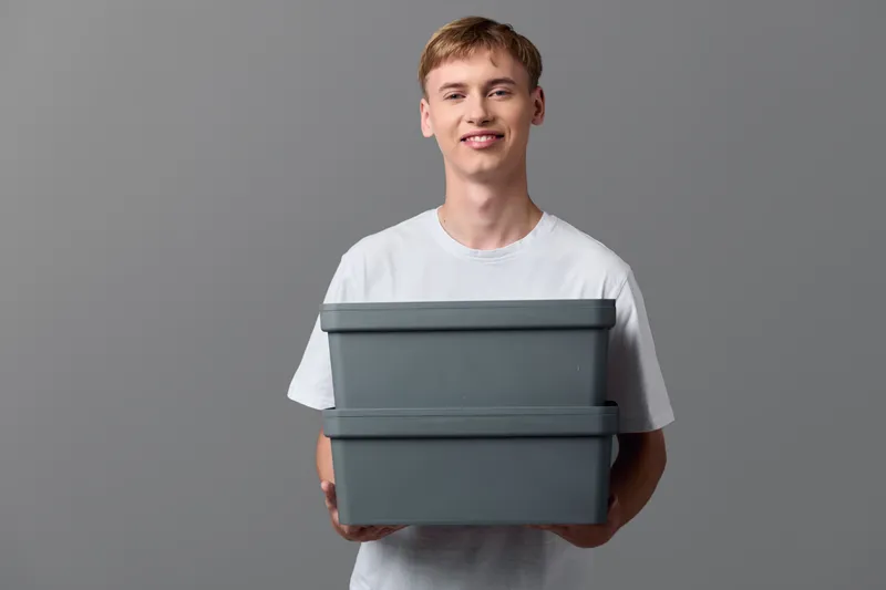 Man in white T shirt holding two gray boxes for delivery packaging and shipping process, ecommerce logistics concept, storage and distribution workflow.