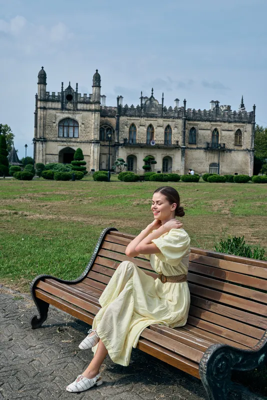woman bench mansion park dress fashion authenticity inclusivity, woman sitting on wooden bench in garden near manor