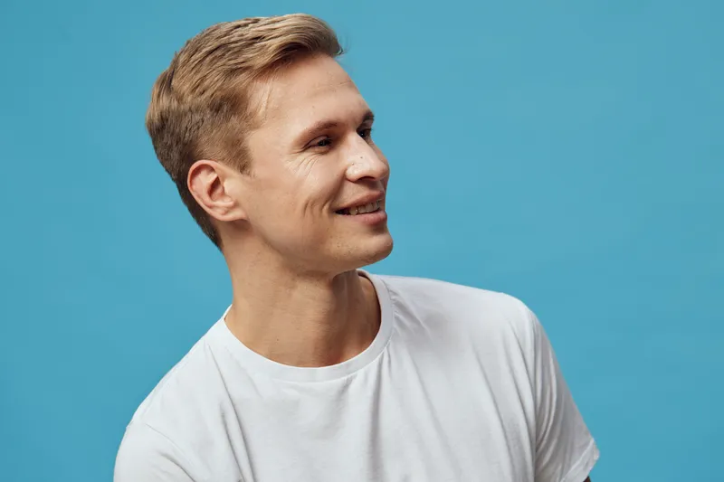 smiling young caucasian man white t-shirt look side isolated on blue background digital nomad remote work concept