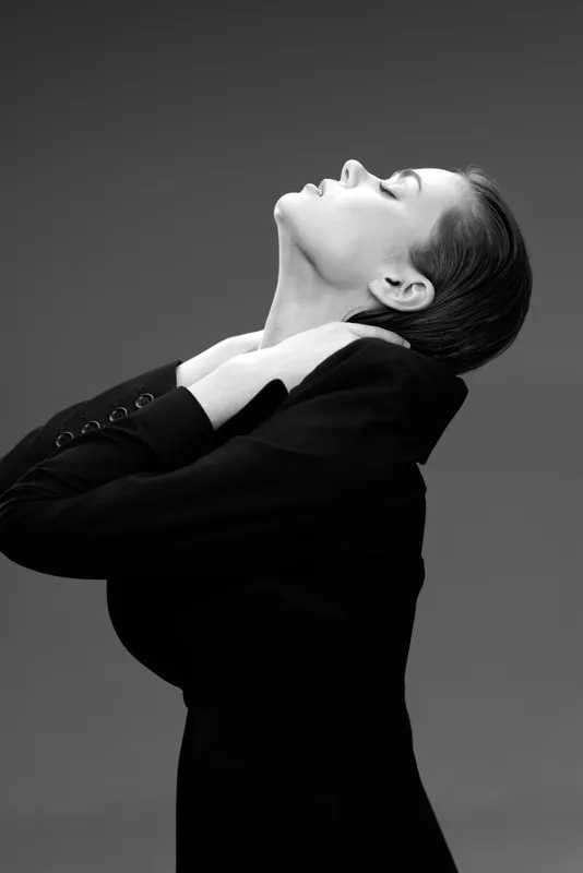 Black and white portrait of a woman in a black dress with closed eyes and elegant posture.